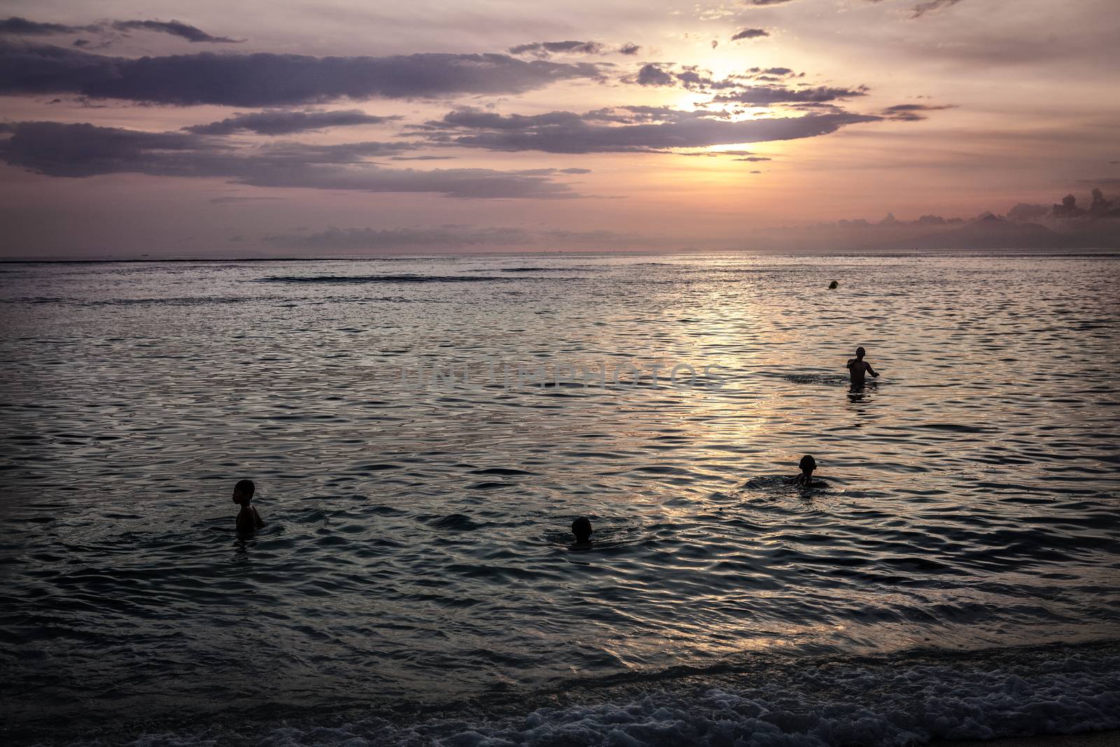 Children swim in the ocean evening sunset at Bali Indonesia