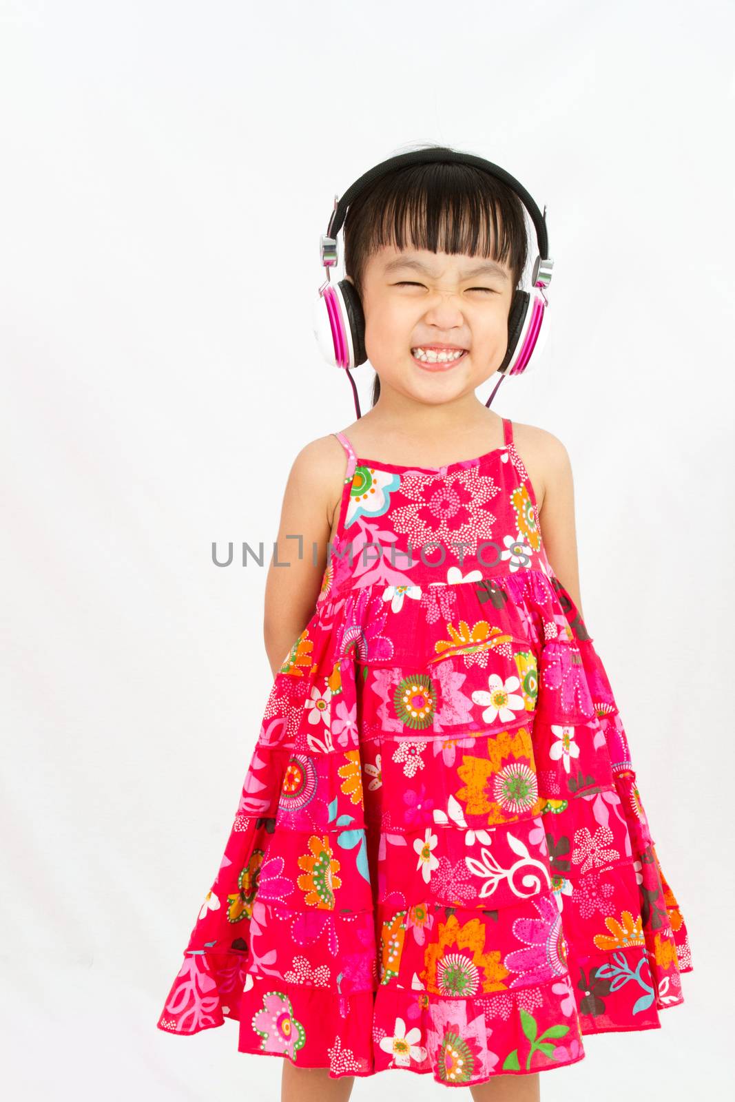 Chinese little girl on headphones smile with plain white isolated background.