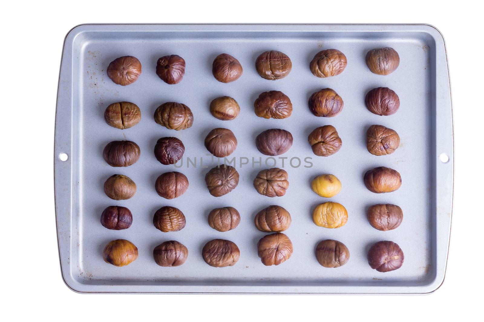 Whole roasted chestnuts on a roasting tray by coskun