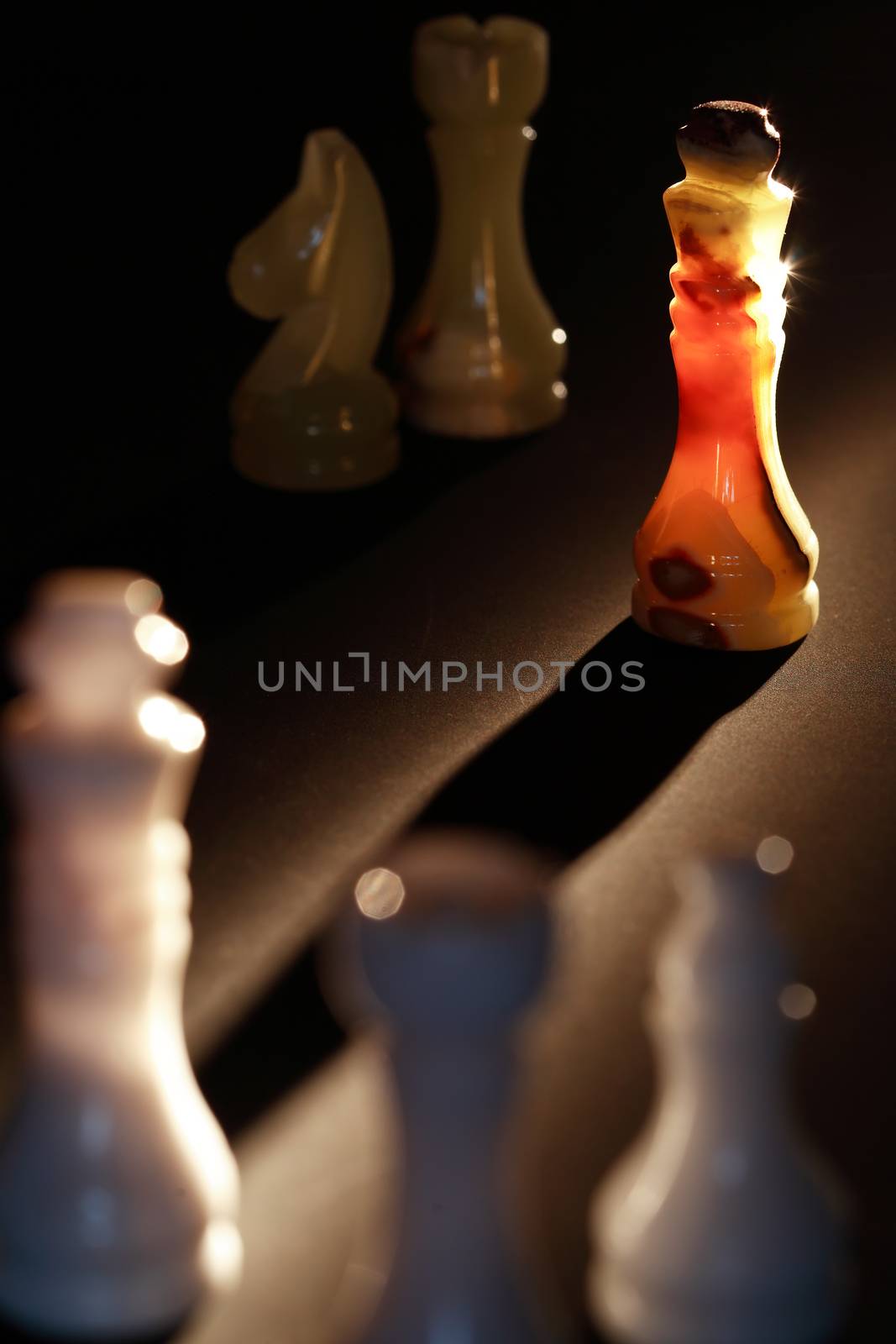 Set of chess pieces made from onyx against light on dark background