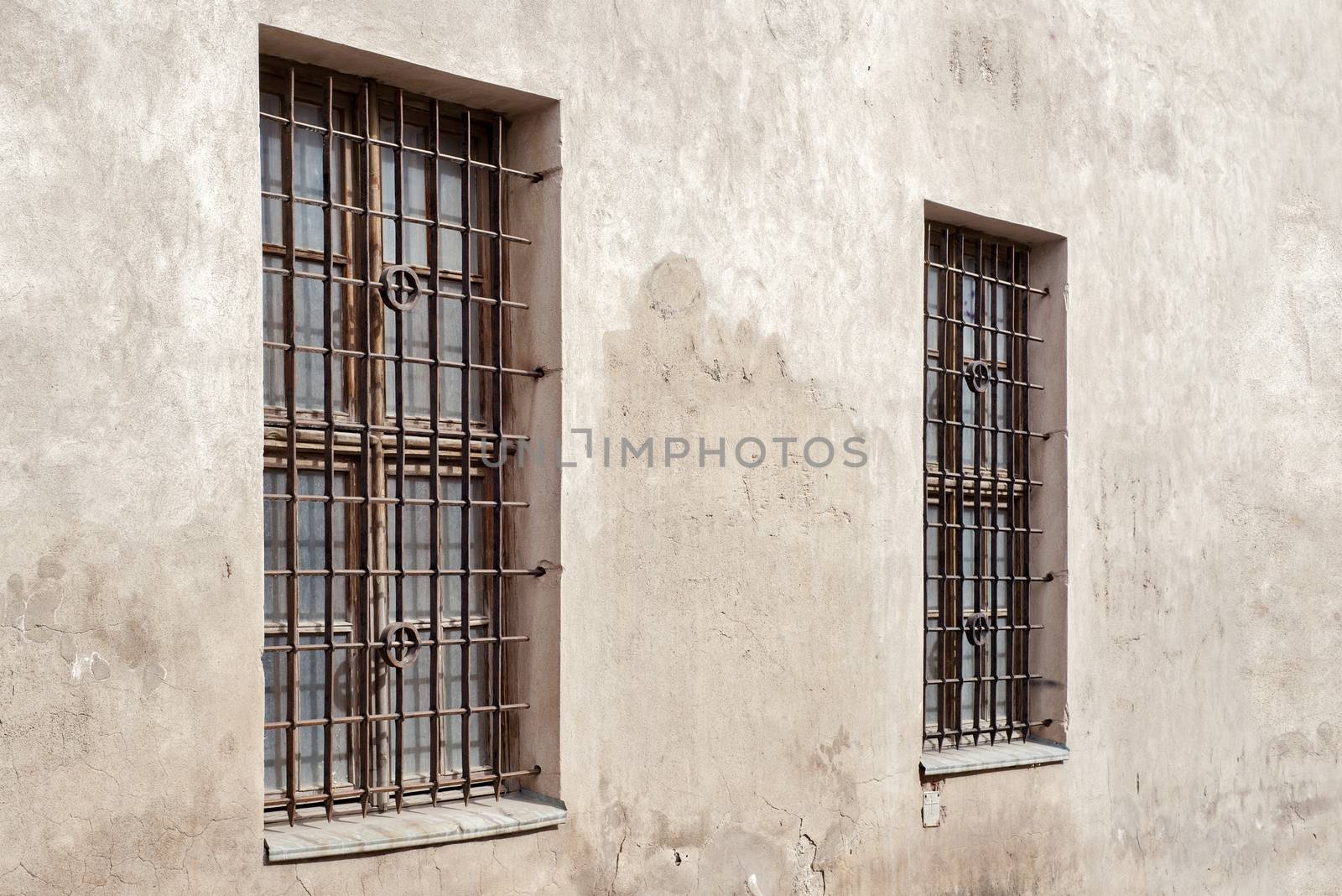 abandoned grunge cracked stucco wall with two window grilles