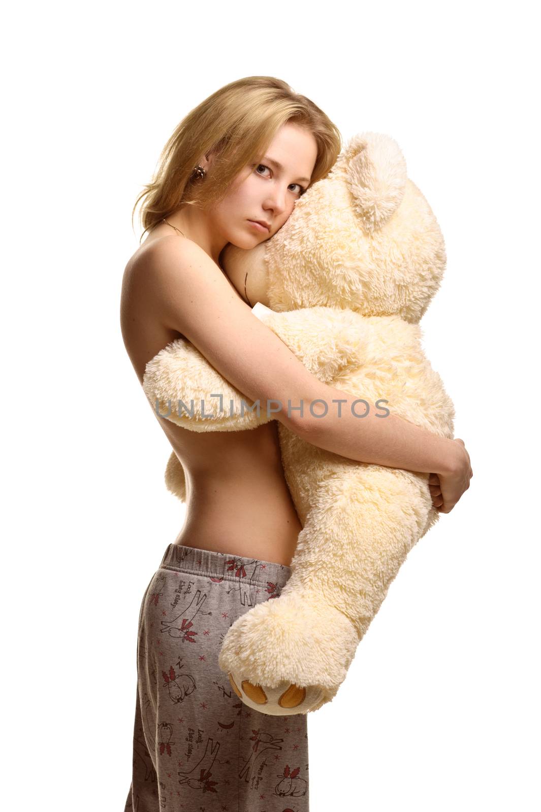 Concept: infantilism, childish, sadness, happiness. Girl in pijamas pants hugging giant plush bear toy isolated on white 