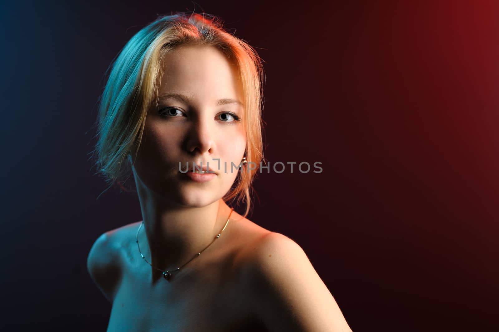 Beautiful girl portrait in blue red light on black background.