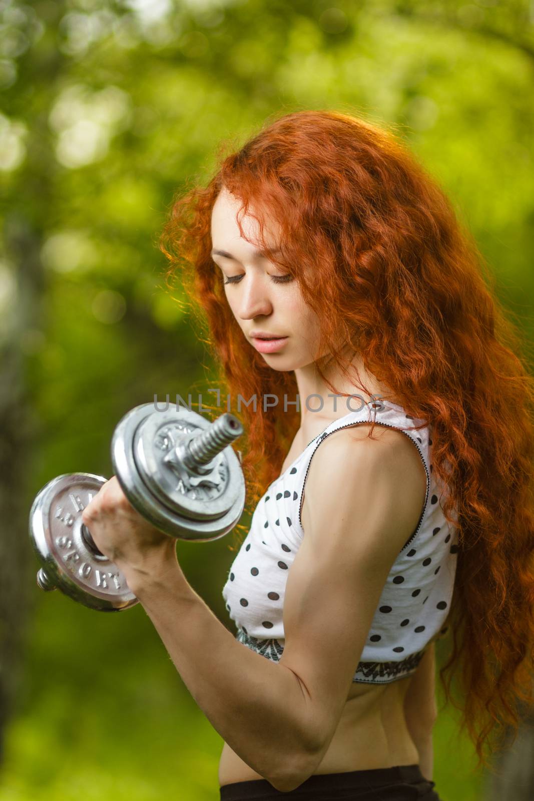 redhead girl exercising with dumbbells at forest by mrakor