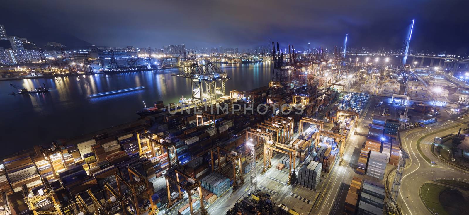 Cargo ship and crane at port reflect on sea bay, hong kong twilight time