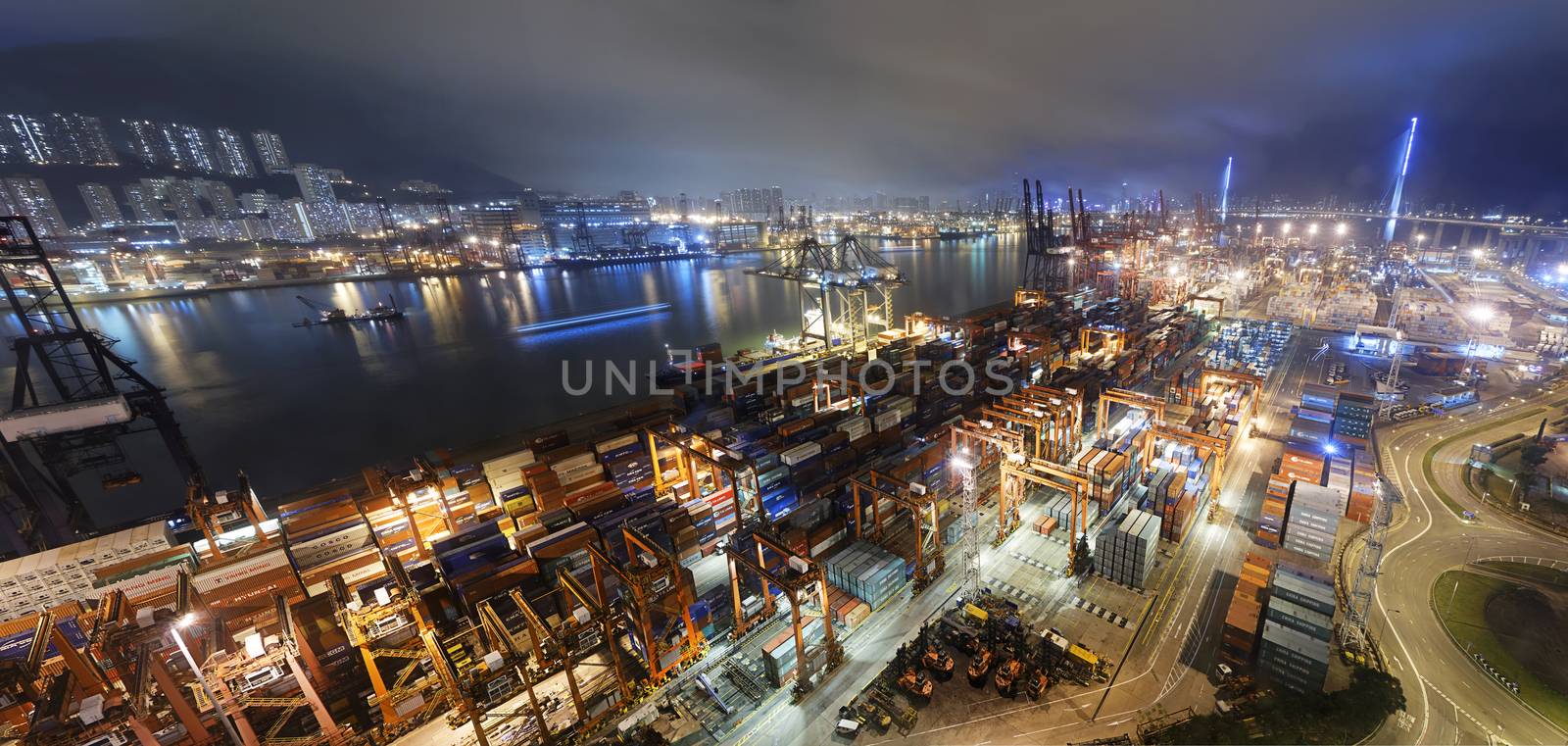 Cargo ship and crane at port reflect on sea bay, hong kong twilight time