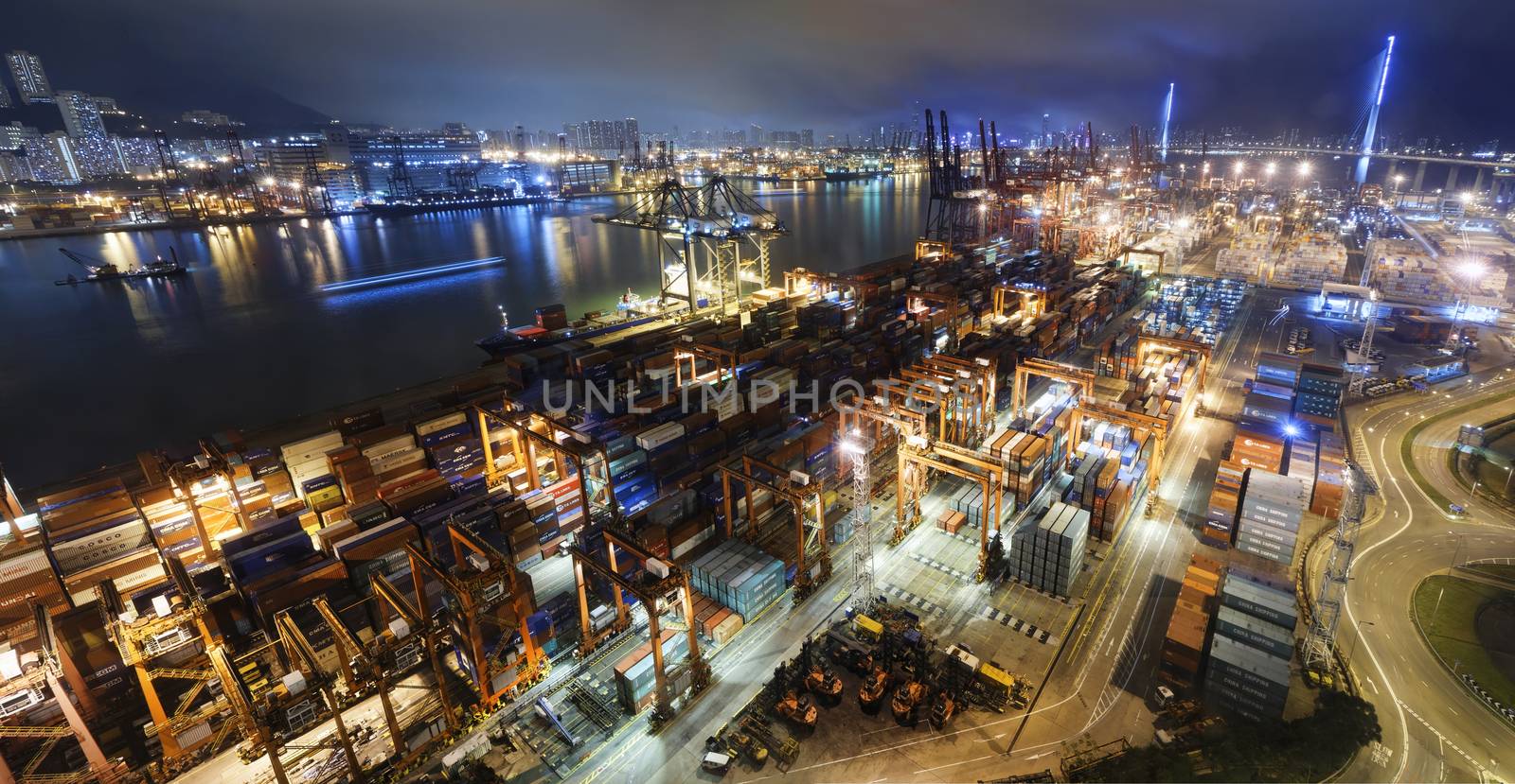 Cargo ship and crane at port reflect on sea bay, hong kong twilight time