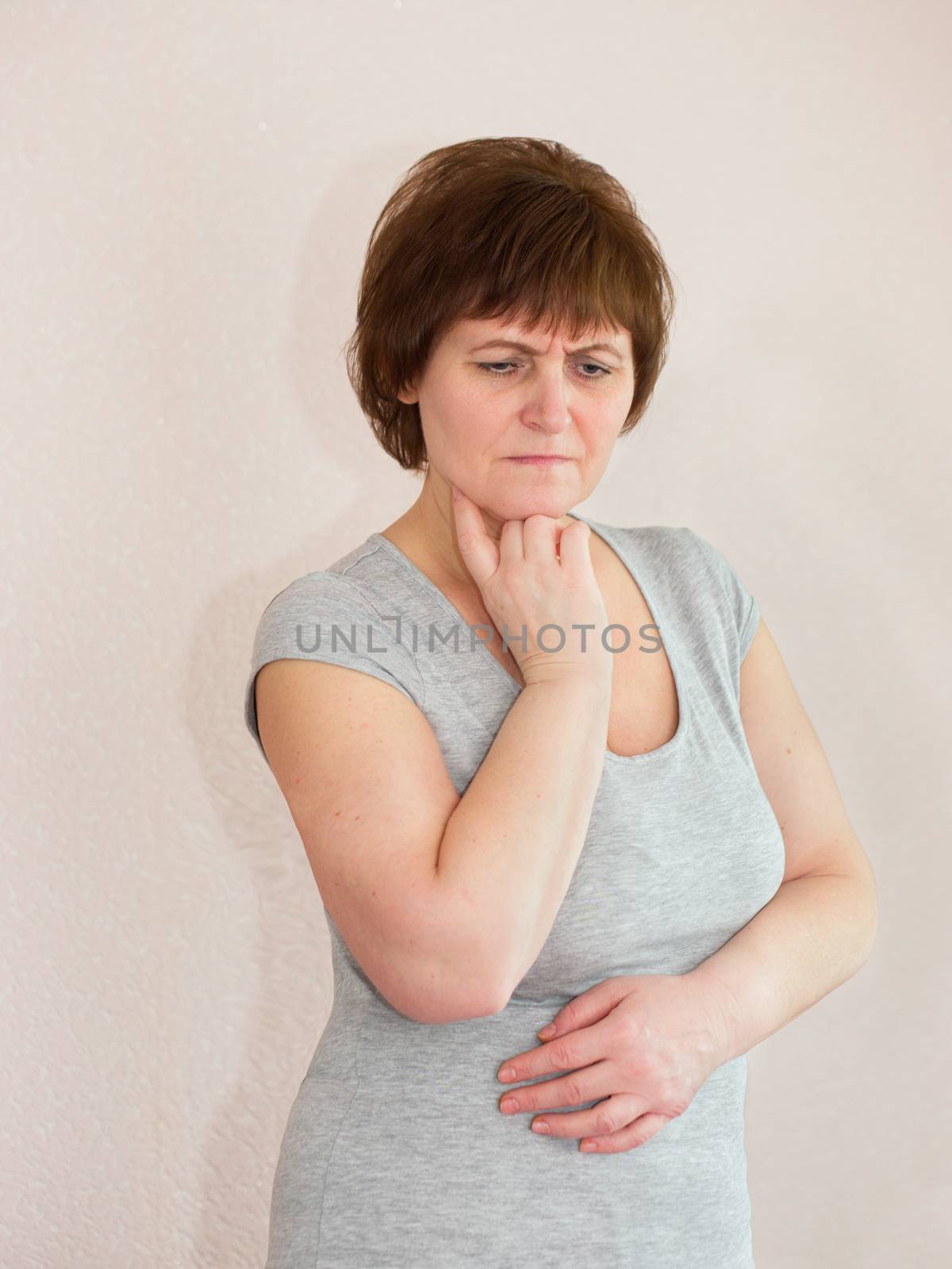 Sad mature adult woman hold a hand under her chin