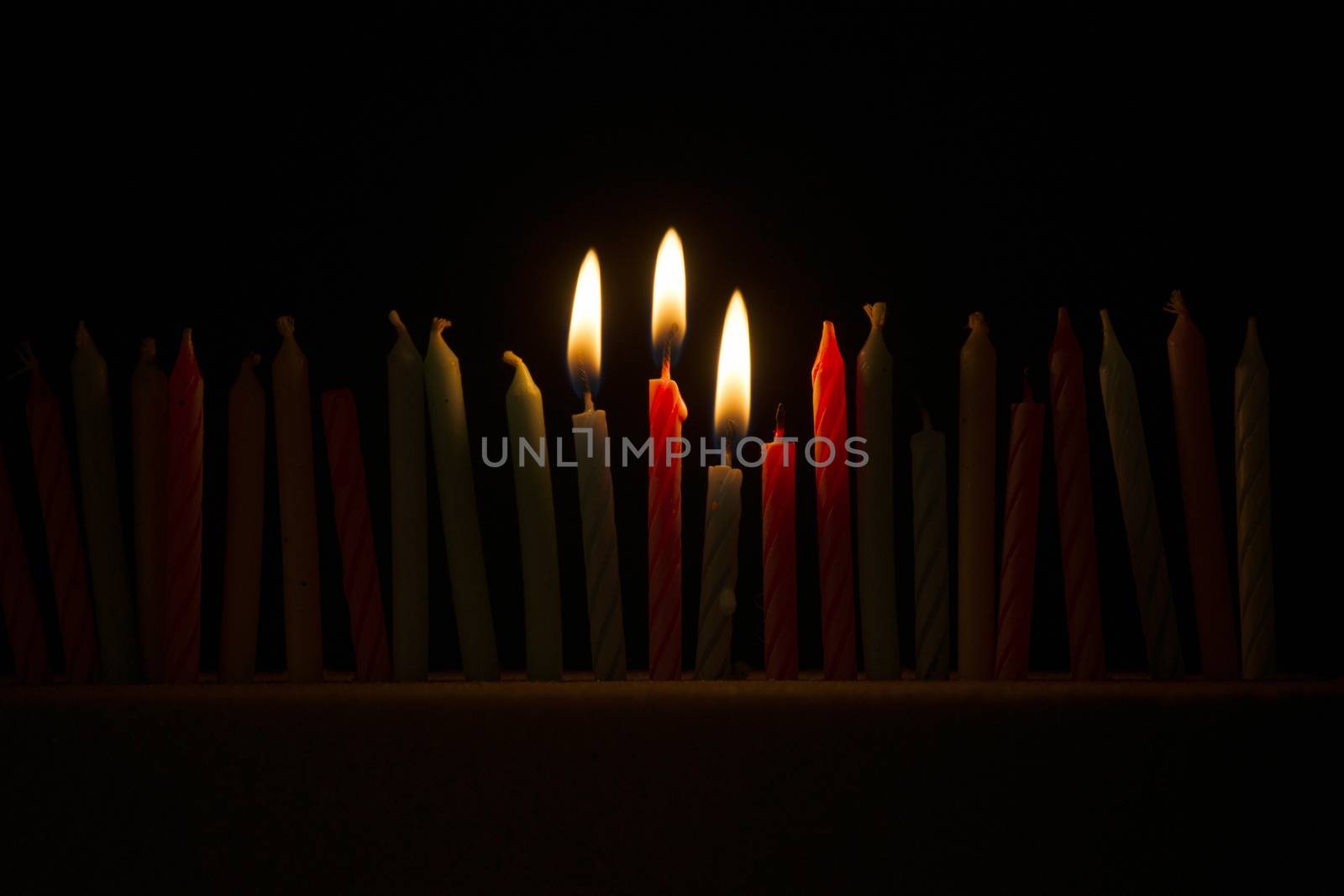 Series of small lighted candles on a black background