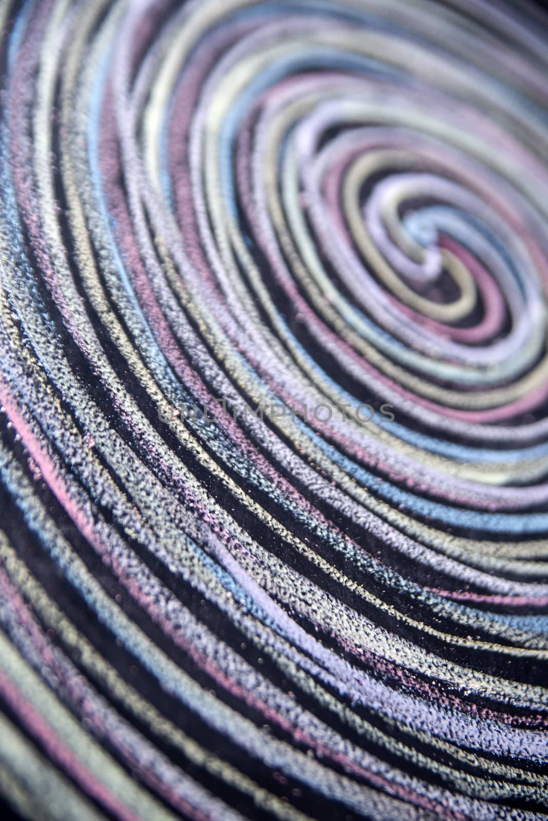 Spirals of different colors drawn with chalk on blackboard