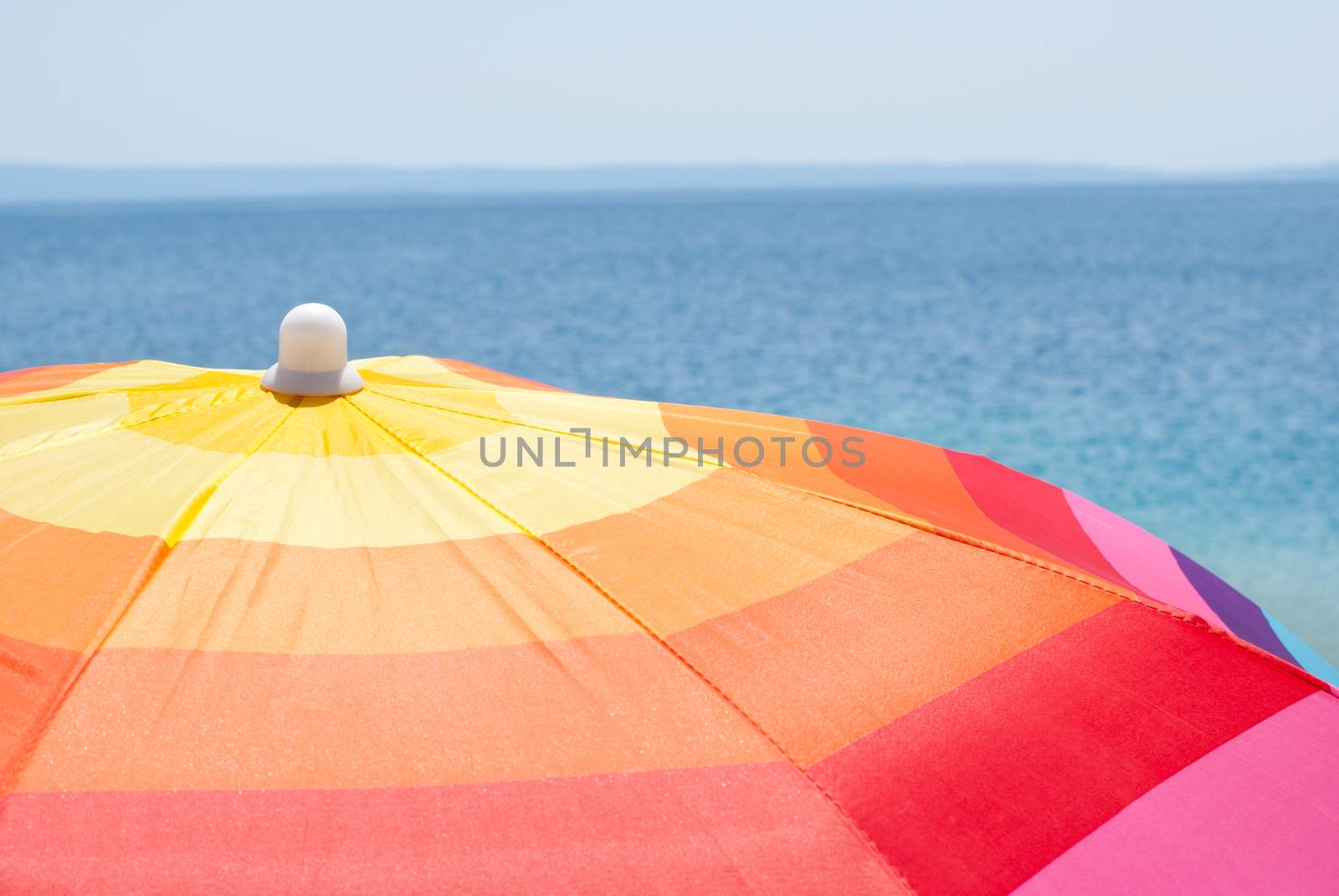 Multicolor beach umbrella on a sunny day and the sea in background