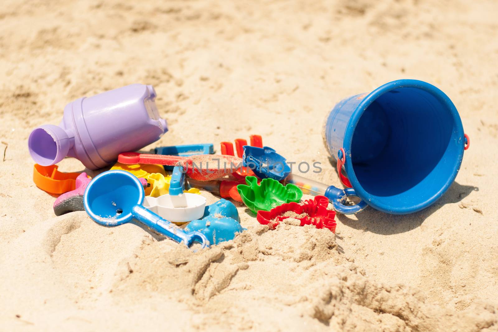 Many plastic toys in the golden sand