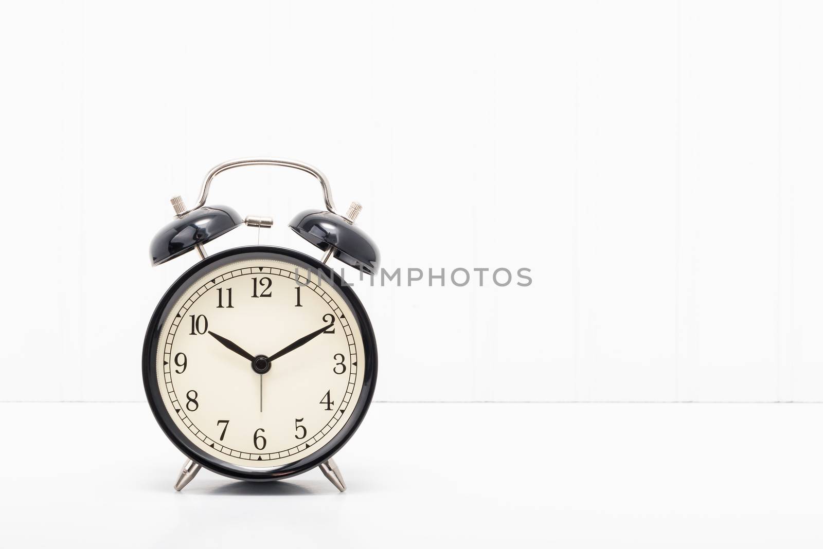 Retro style alarm clock on a simple background with ample copy space.