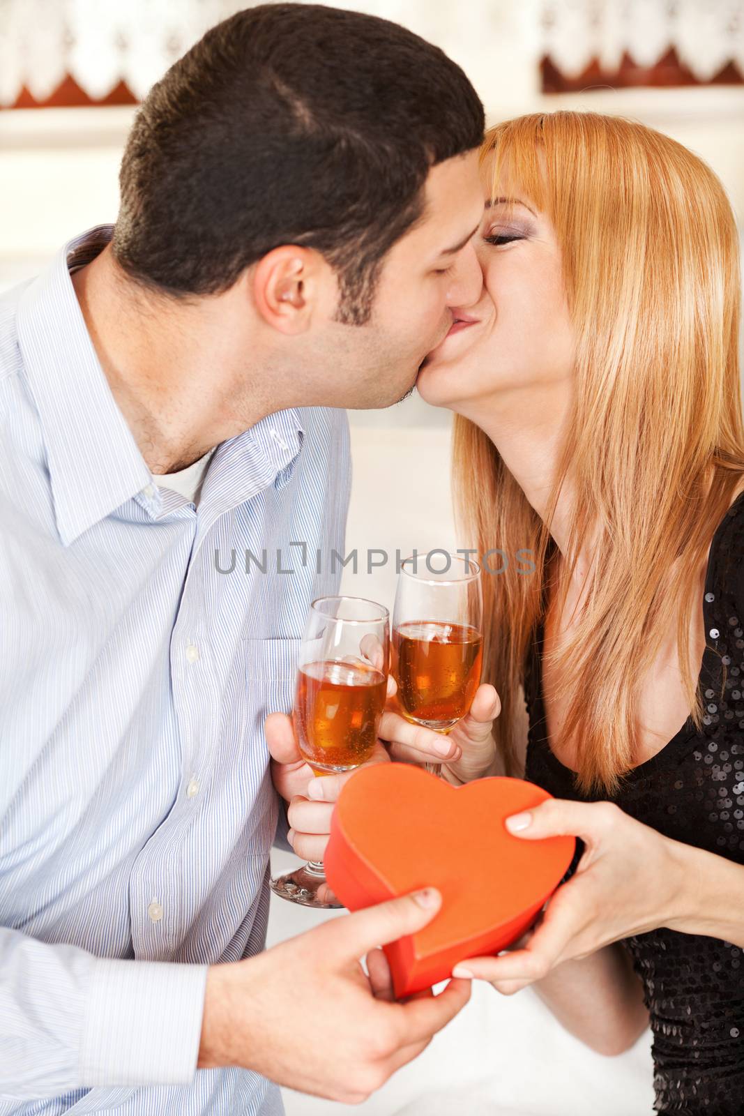 Happy young couple toasting their anniversary with champagne and kissing each other