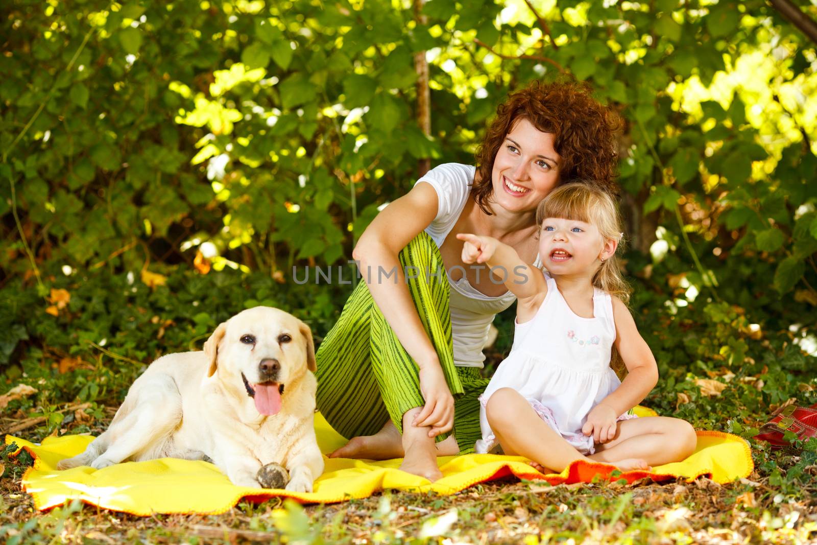 Beautiful mother and daughter relaxing in nature with their dog