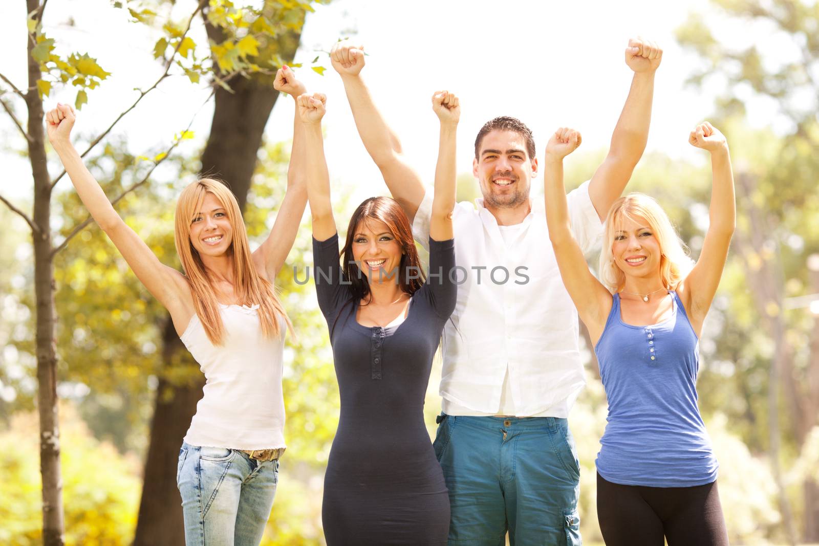 Happy friends in nature with raised arms