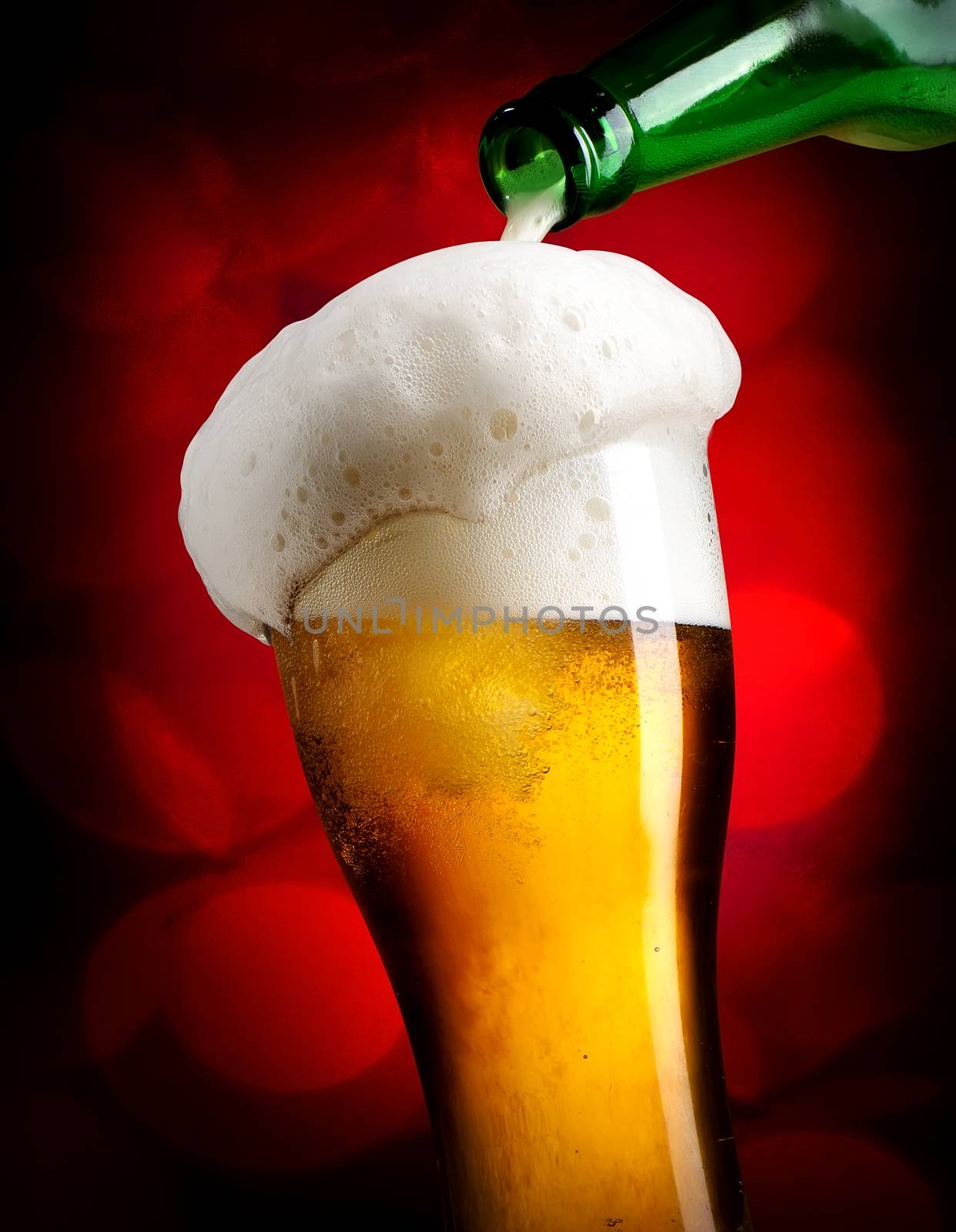 Beer pouring from bottle into glass on red background