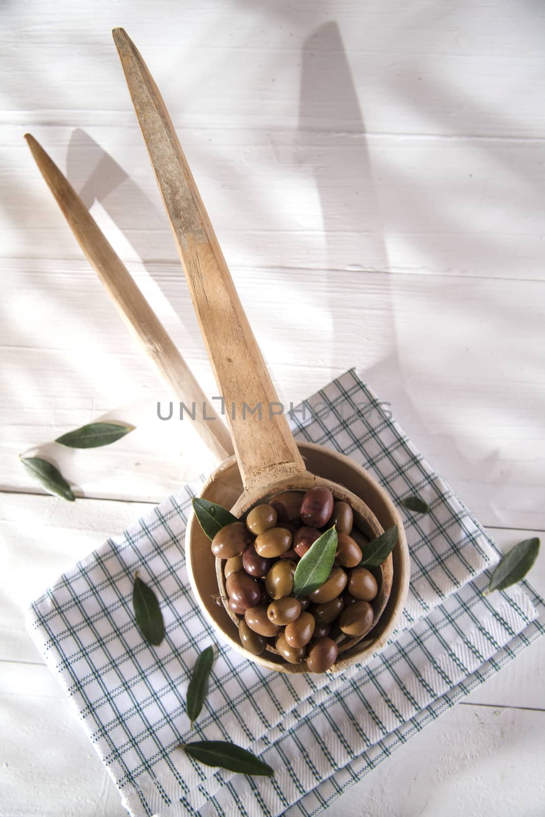 Presentation of a small group of black olives on wooden ladle
