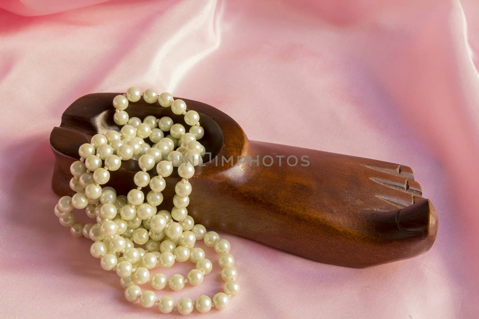 Pearl Necklace in wooden ashtray on a pink silk