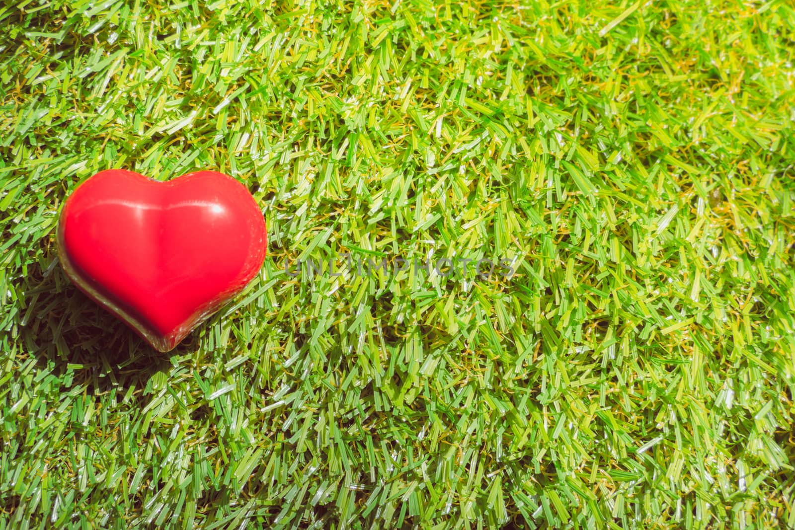 closeup of a red heart on the grass by teerawit