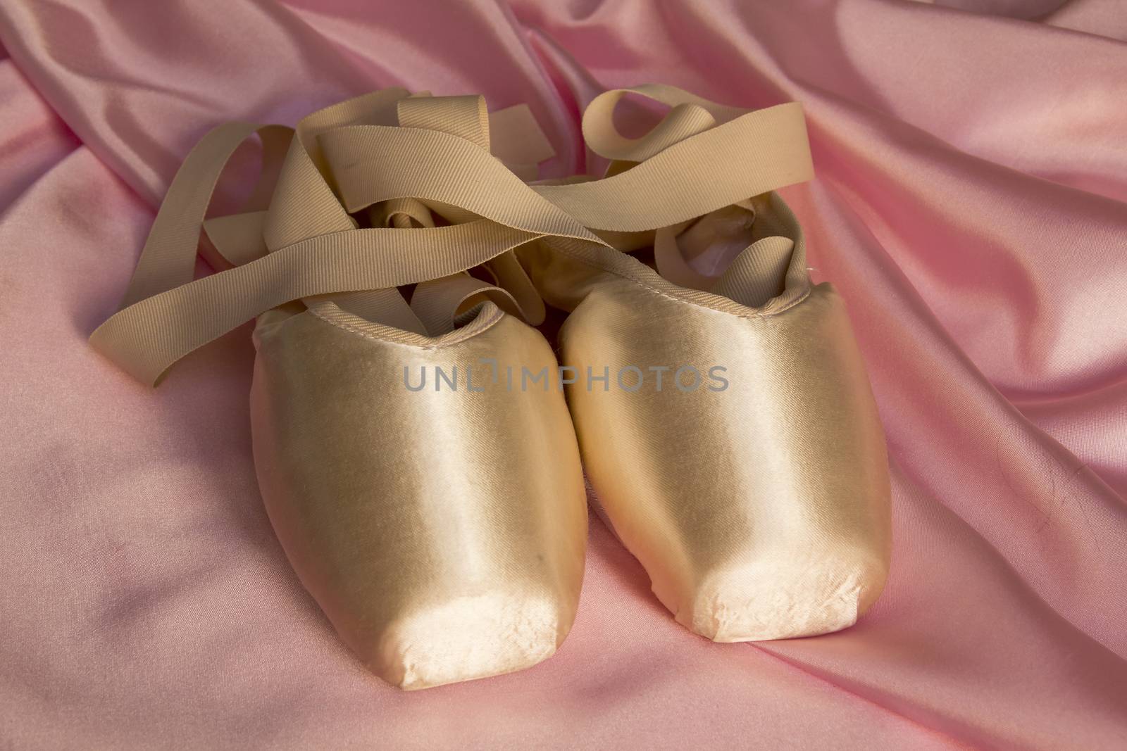 Ballet shoes on delicate pink silk background