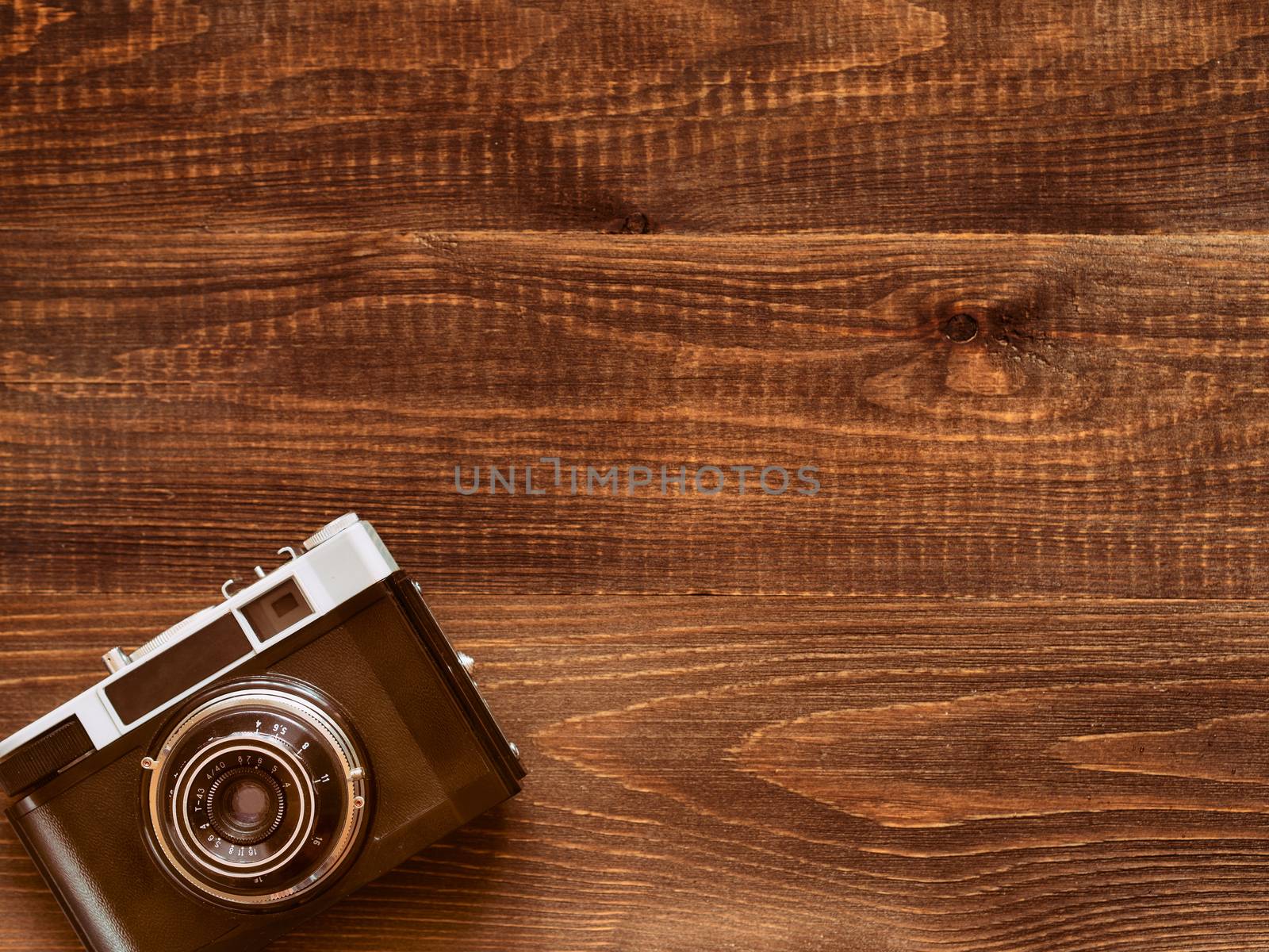 Wooden table background with old vintage camera. Flat lay or top view