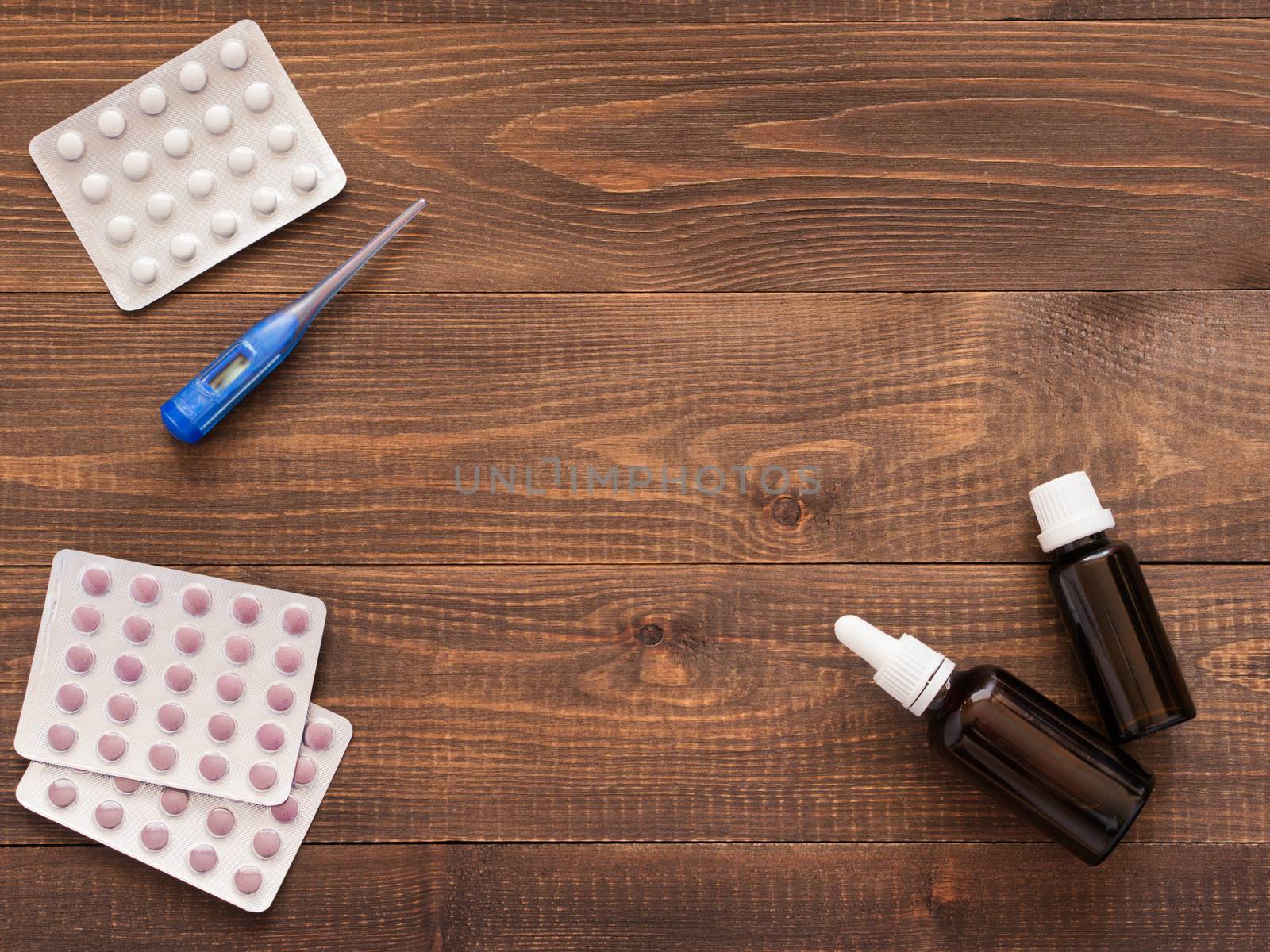 medications and thermometer on a wooden background by fascinadora