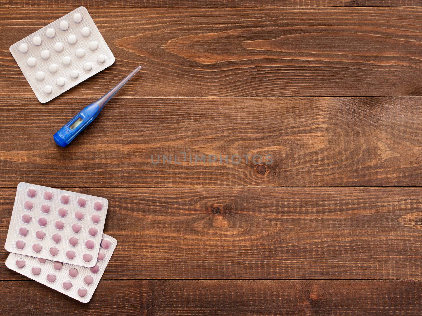 tablets and electronic thermometer on a dark wooden background with copy space. Flat lay or top view