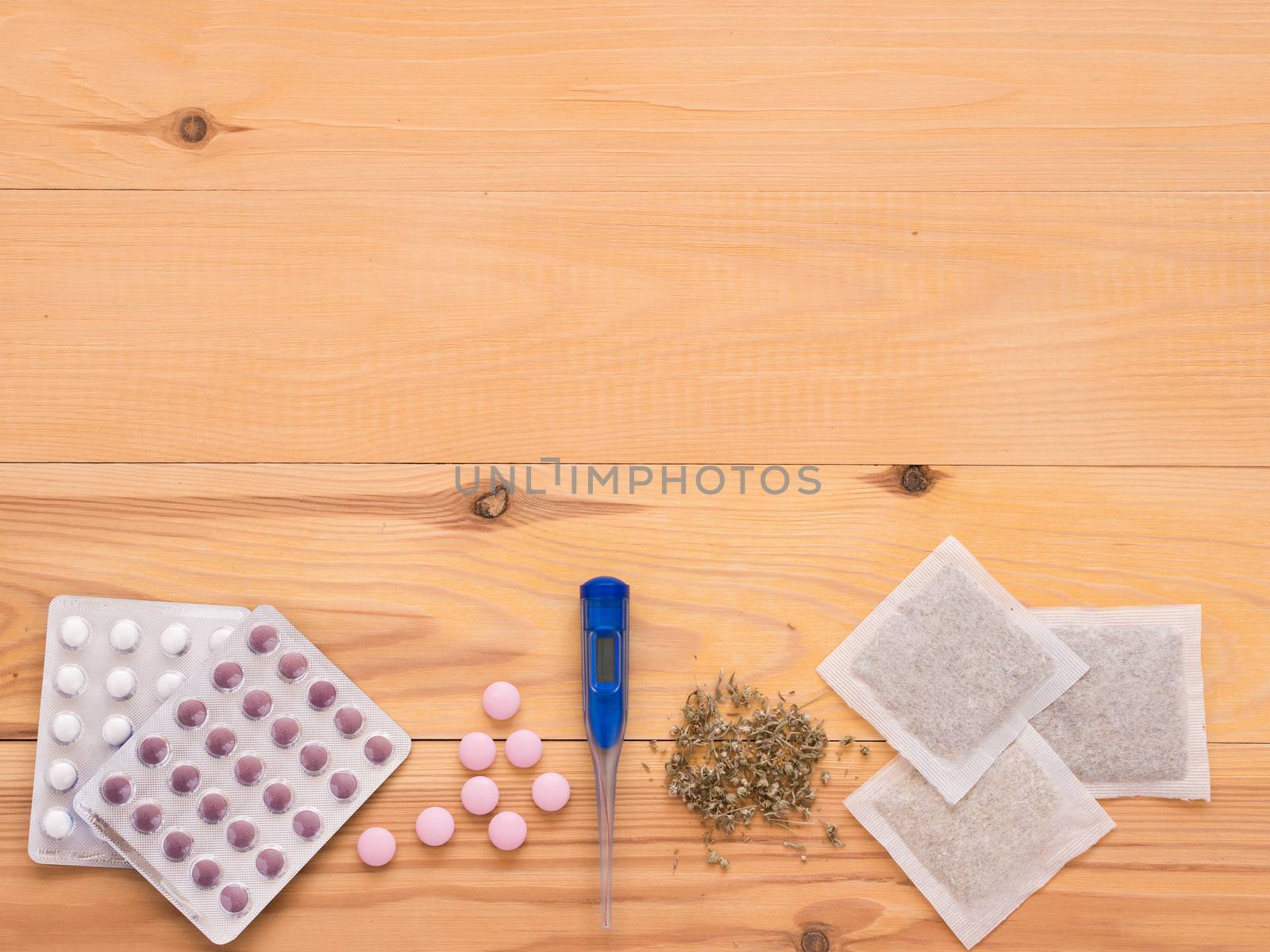 tablets, drops, herbals and thermometer on a light wooden background with copy space. Herbal medicine VS Chemical medicine the alternative healthy care. Flat lay or top view