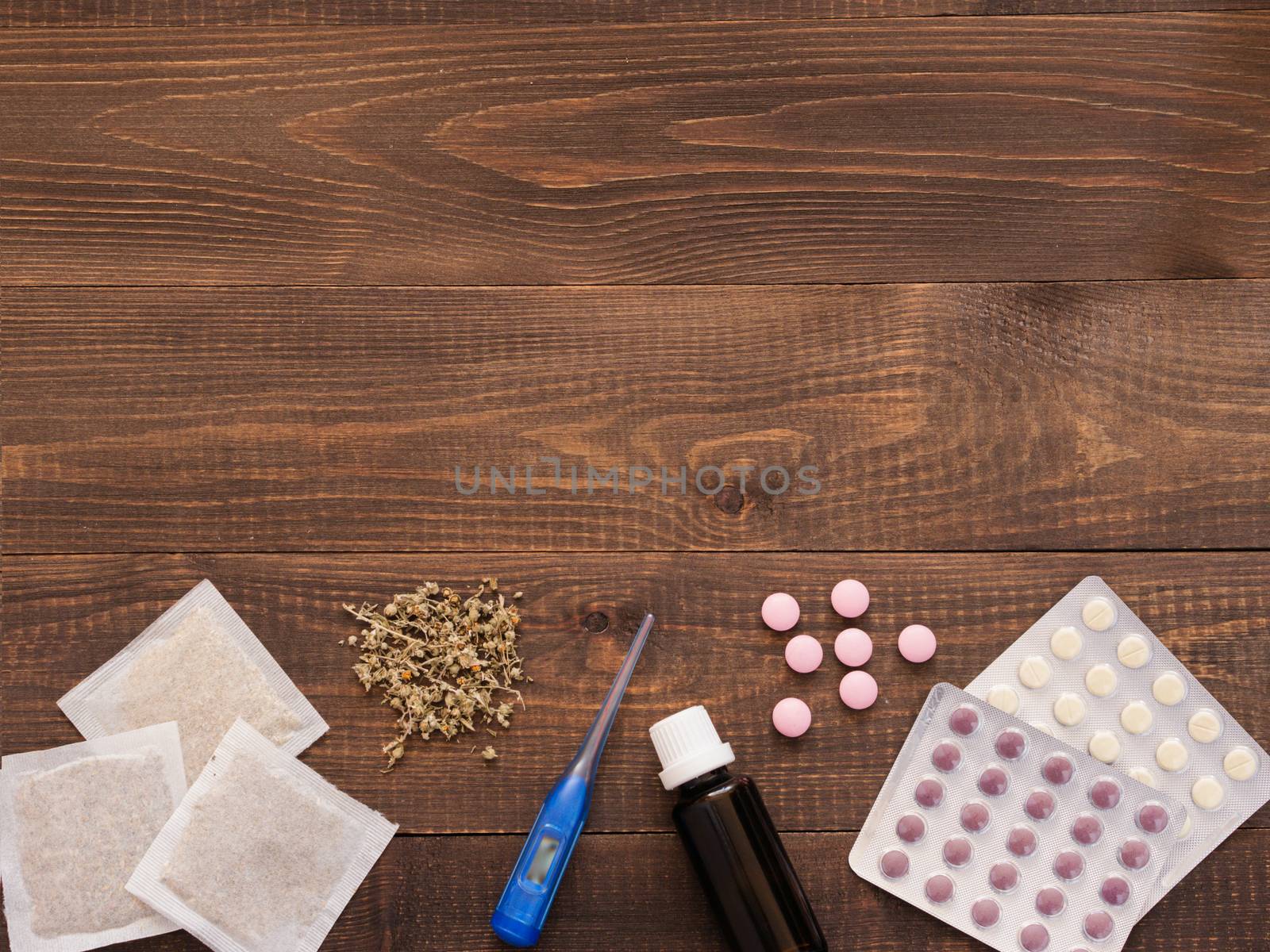 tablets, drops, herbals and thermometer on a dark wooden background with copy space. Herbal medicine VS Chemical medicine the alternative healthy care. Flat lay or top view