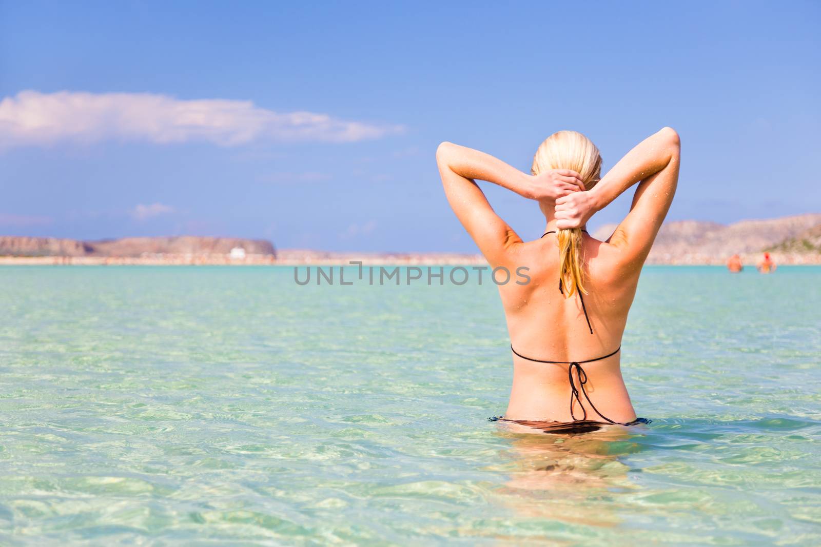Young caucasian woman enjoying summer swimm in picture perfect turquoise sea lagoon on Balos beach, Crete, Greece.