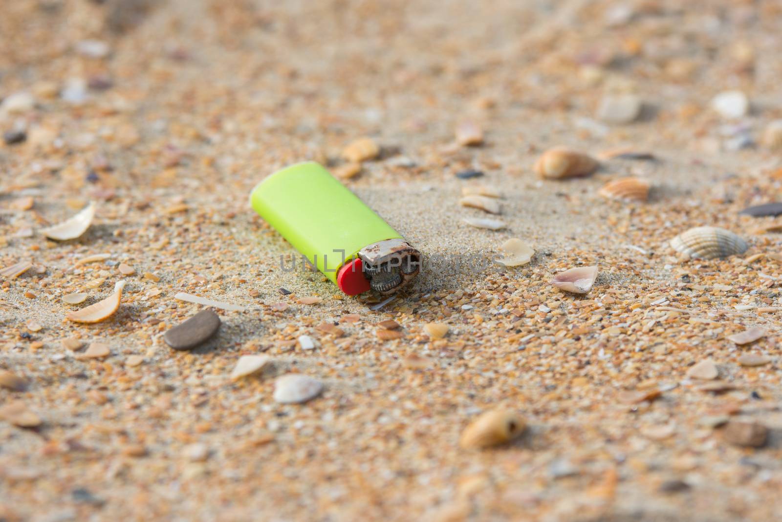 Old used lighter in the sand on the beach