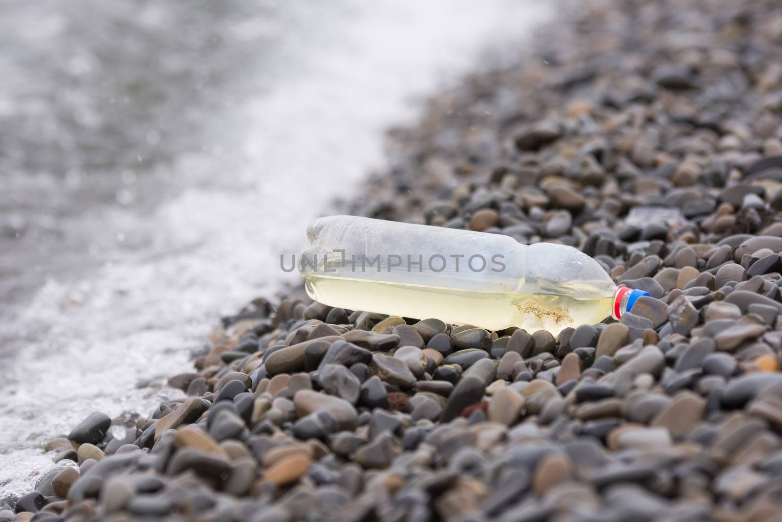 Plastic bottle lying on the pebbly seashore