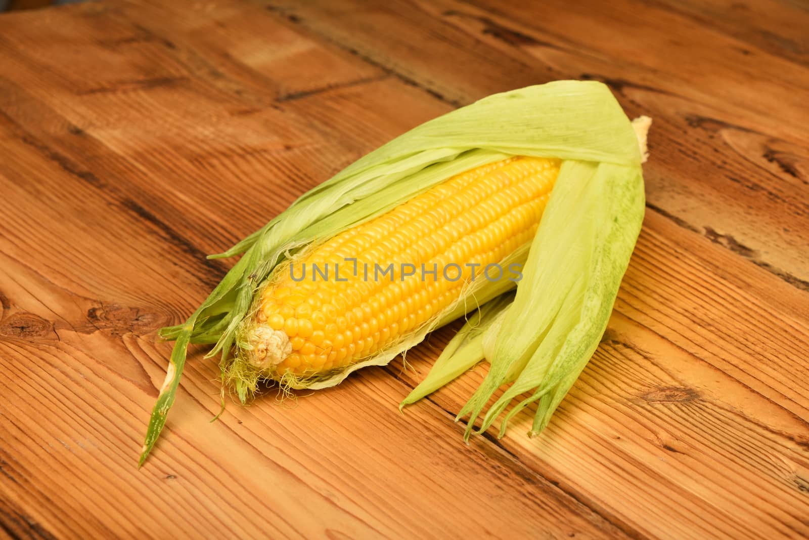 One open corn cob on vintage wooden surface by BreakingTheWalls