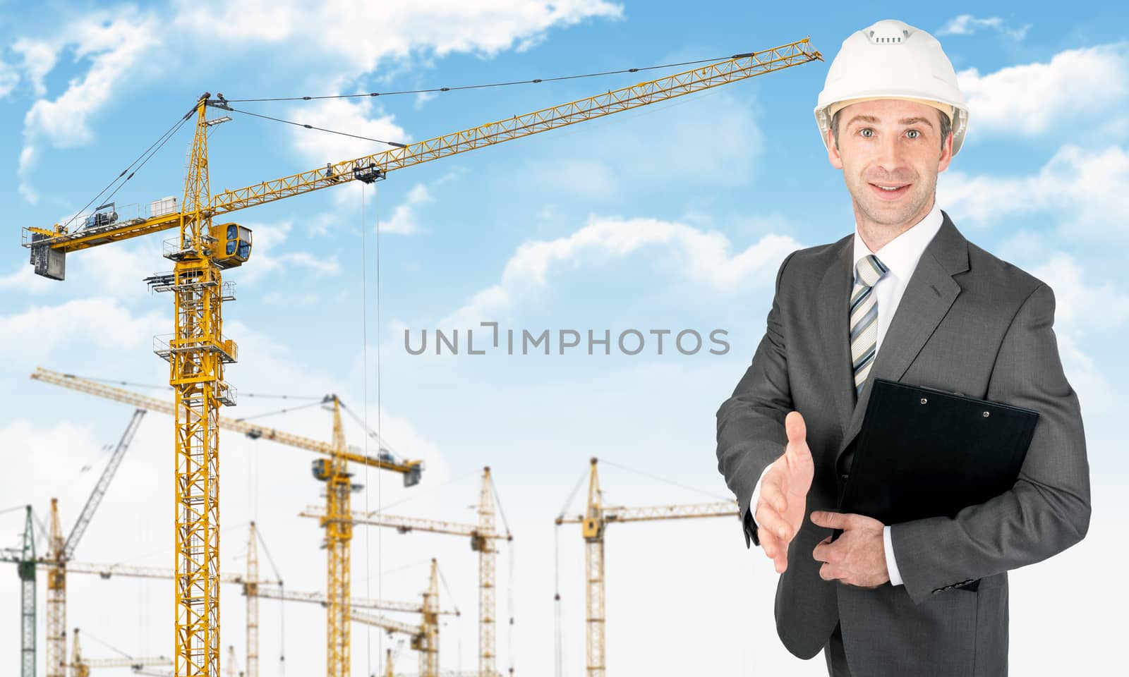 Smiling businessman in helmet holding folder on building site