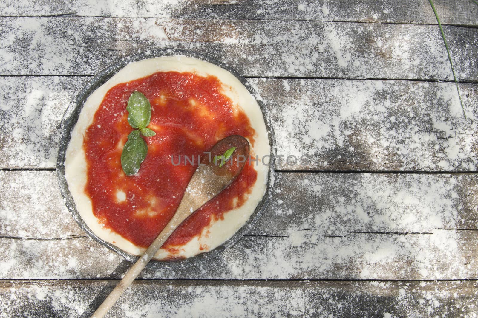 Preparing pizza made with tomato basil and mozzarella 