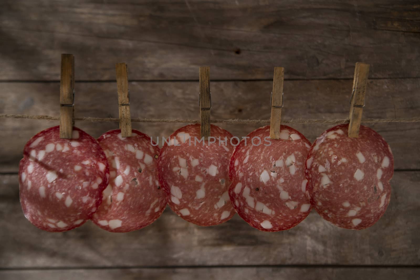 Presentation of slices of salami hanging by a thread