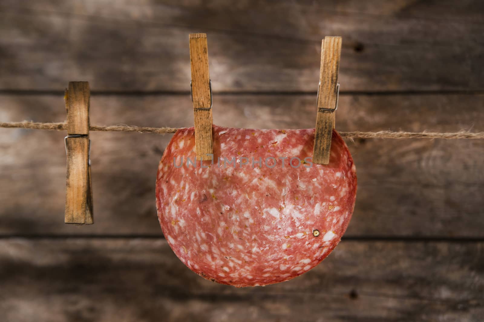 Slices of salami hanging by fotografiche.eu