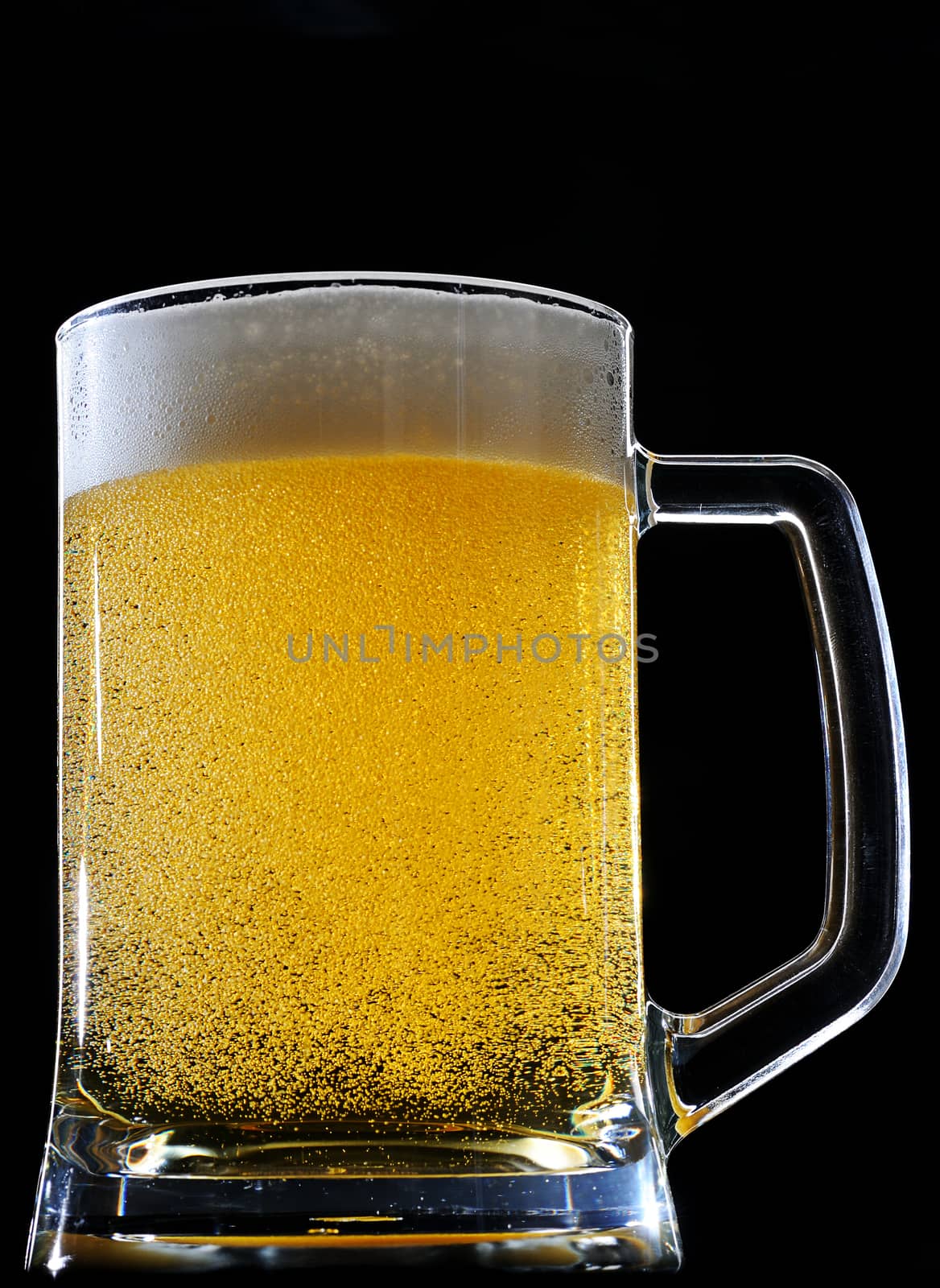 Sparkles in yellow beer glass on black background