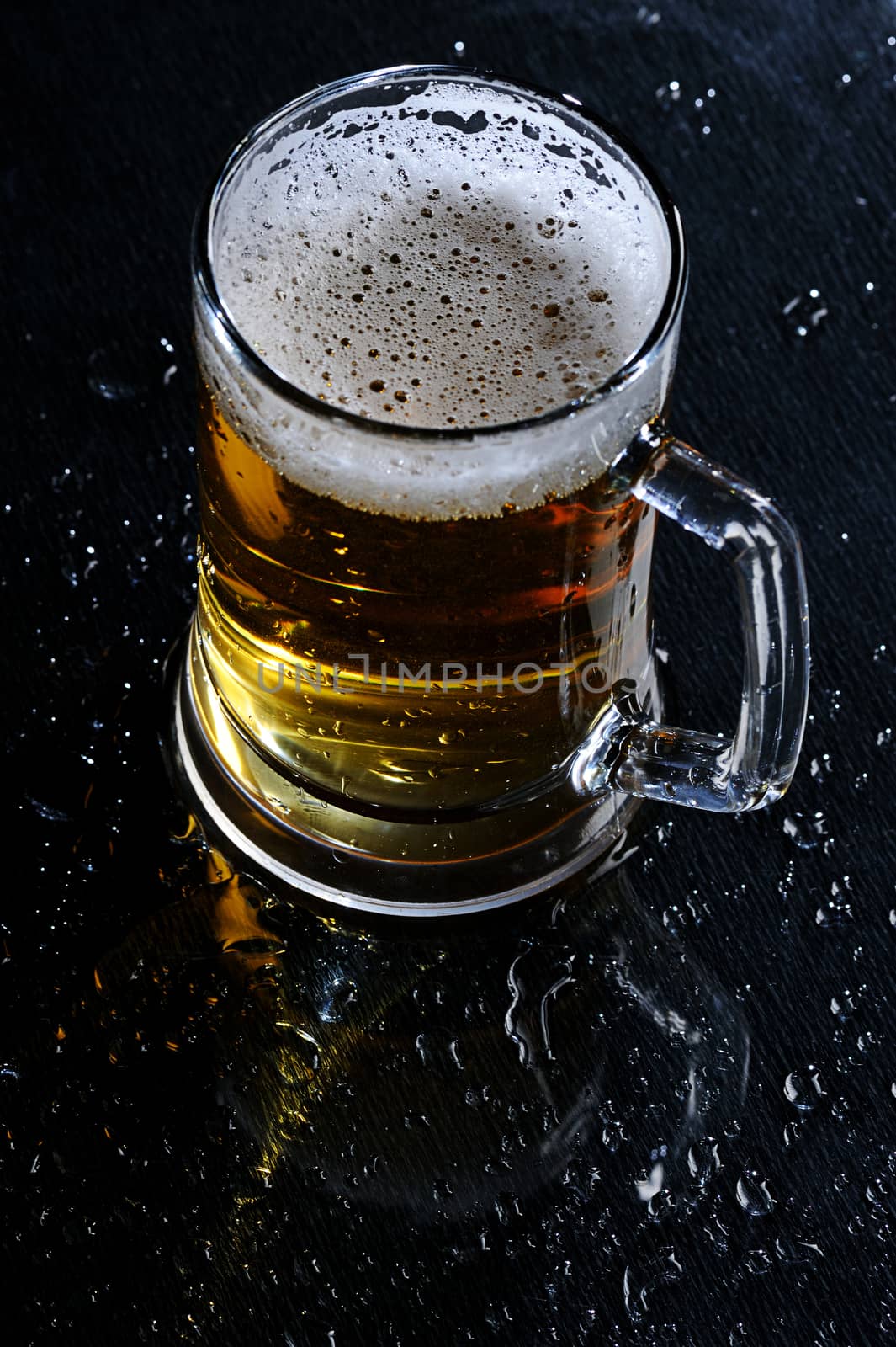 Glass beer with foam on wet  black table