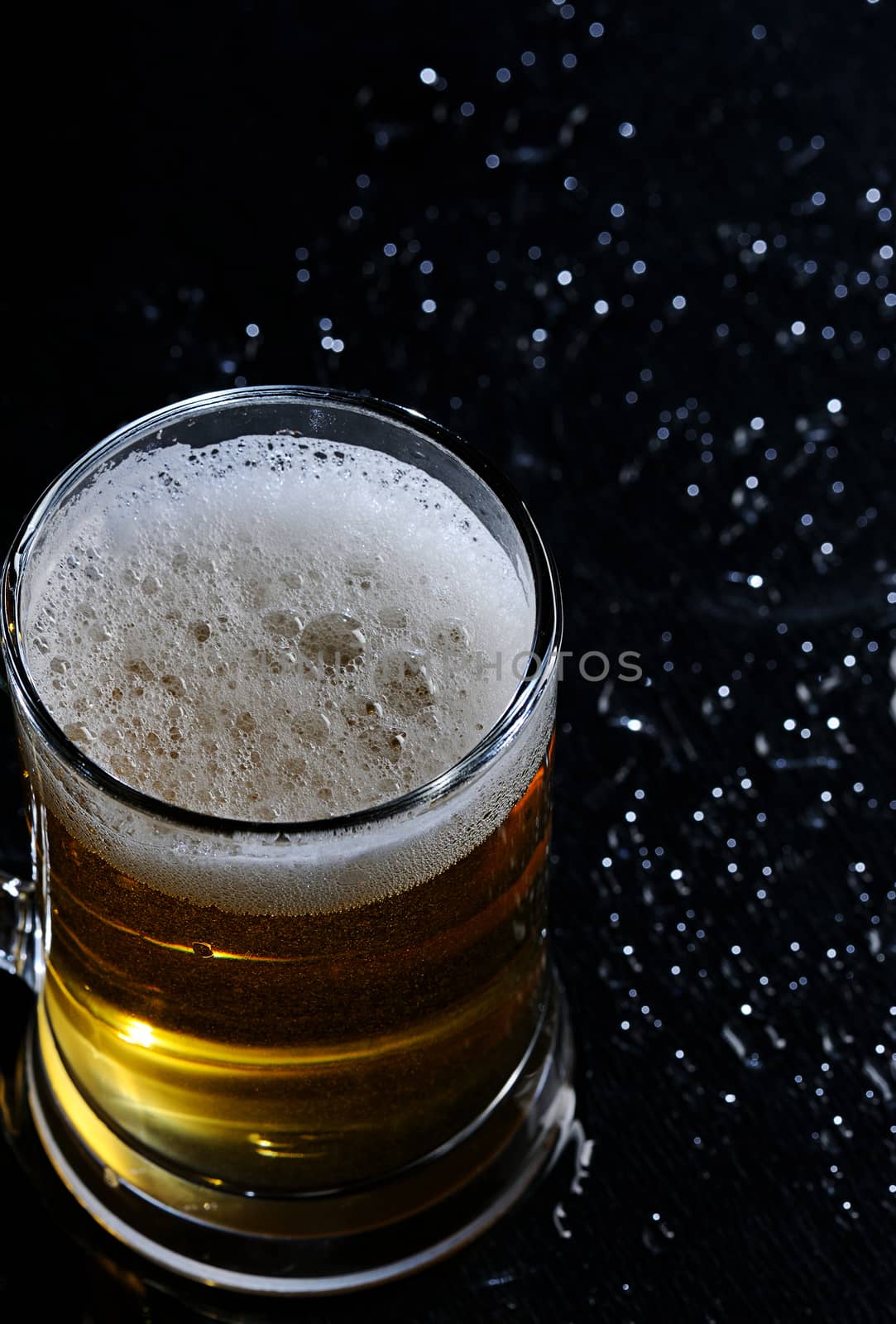 Beer with foam in glass on black background