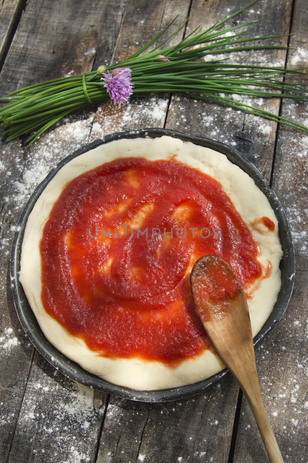 Preparing pizza made with tomato and chives