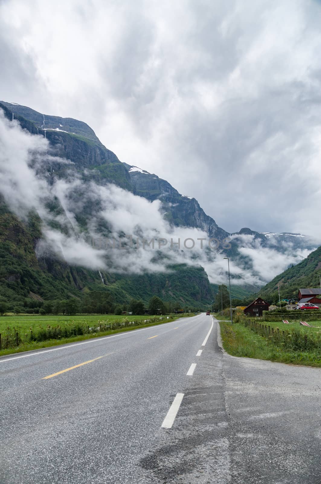 Misty mountains covered by clouds and vanishing road near Gudvangen village, Norway