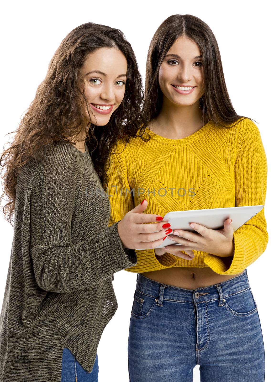 Studio portrait of two beautiful girls holding and showing something on a tablet