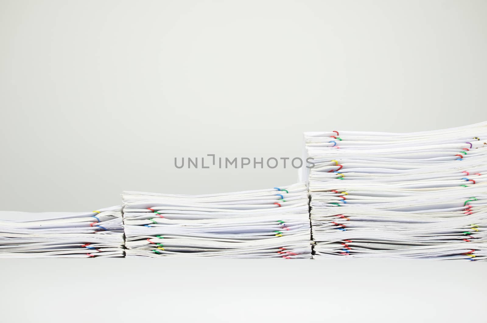 Overload paperwork of report with colorful paperclip on white table.