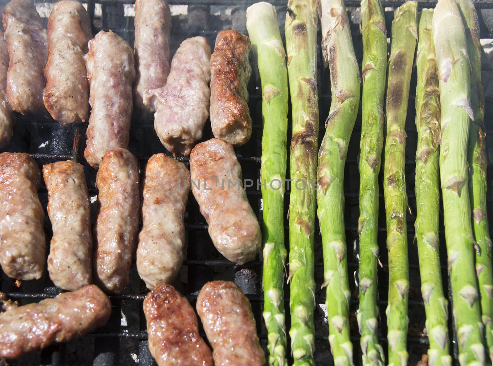 Cevapi, famous Balkan dish, and asparagus on a grill.