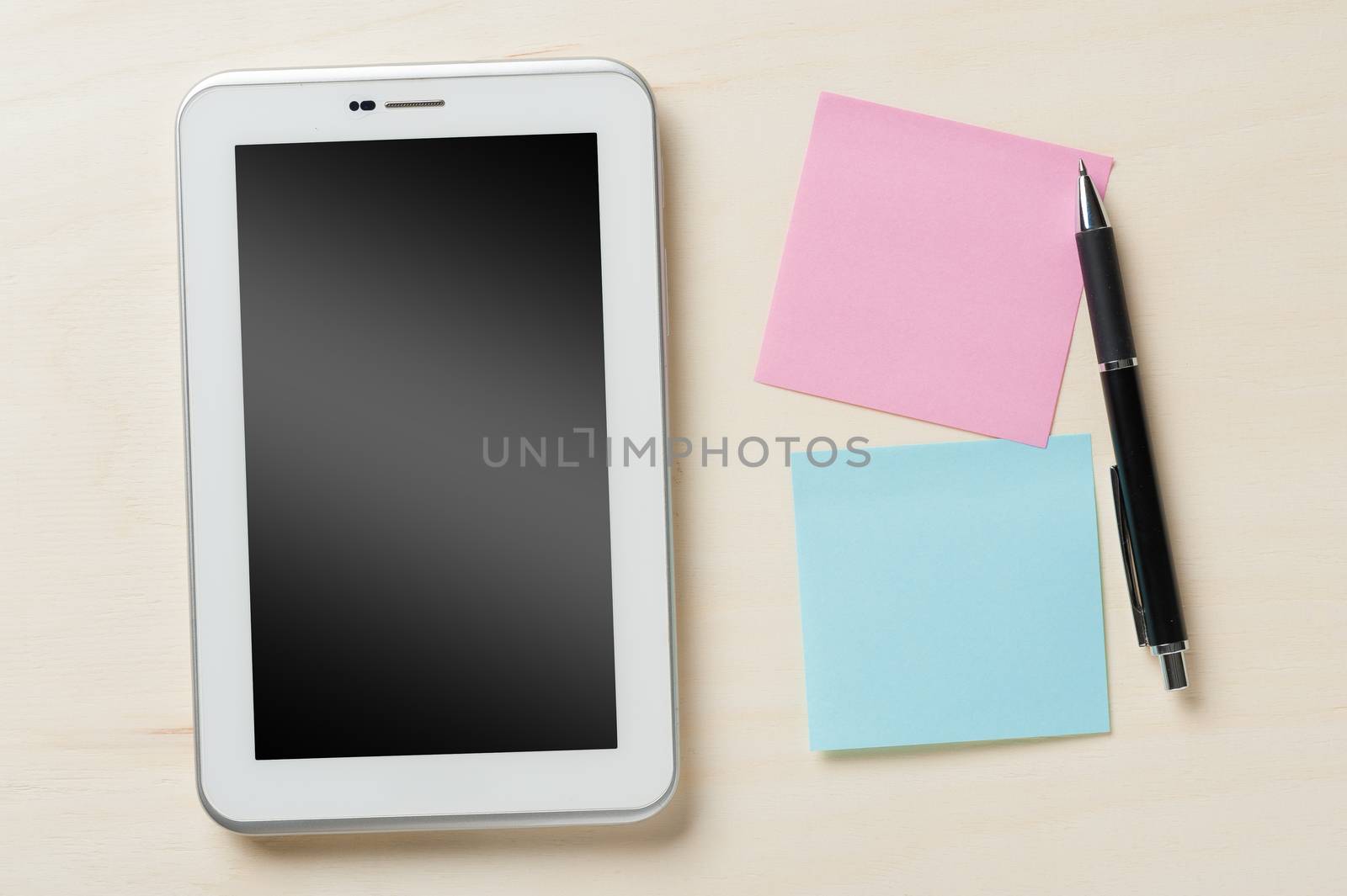 Small tablet pc with blank area on touchscreen and sticky paper with blank copy space on wood table