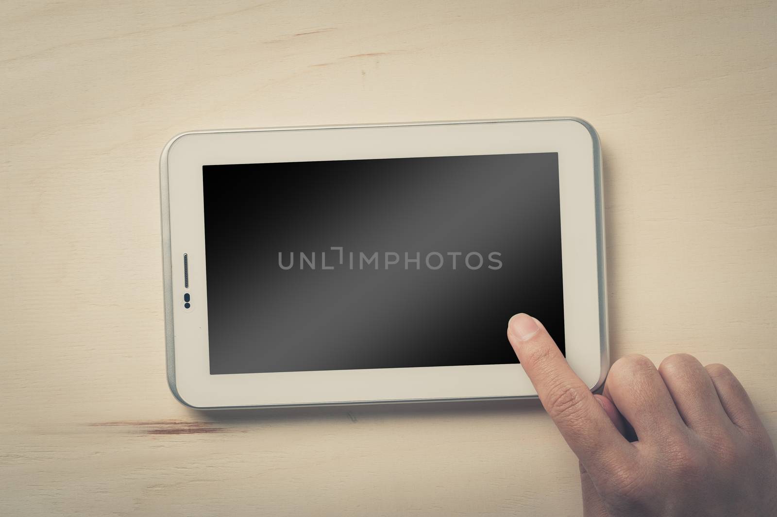 Young man right hand touching on small tablet with blank area on touchcreen on wood table