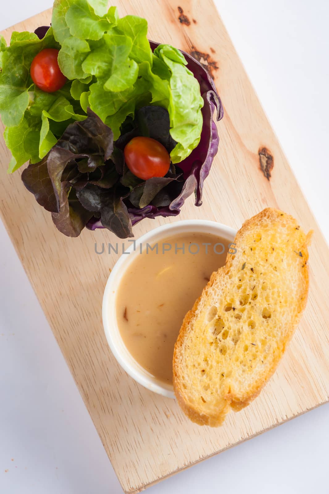 Mushroom soup in ceramic cup with toast and freash vegetables on wood plate. Clean and healthy eating concept food.