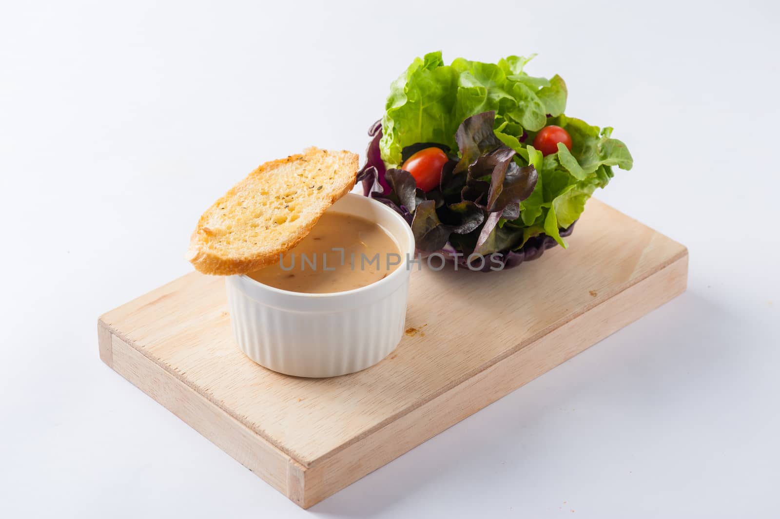 Mushroom soup in ceramic cup with toast and freash vegetables on wood plate. Clean and healthy eating concept food.